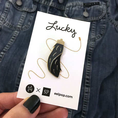Black and gold lucky rabbit's foot pin on illustrated backing card Black and gold lucky rabbit's foot pin on illustrated backing card